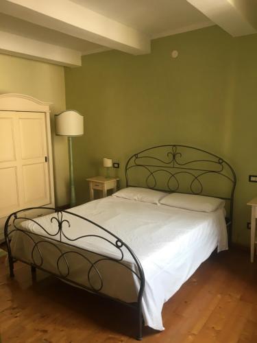 a bedroom with a bed with white sheets and green walls at La Casina del Borgo in Abbadia San Salvatore