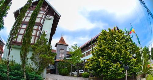 um edifício com bandeira e um edifício com árvores em Hotel Aconchego da Serra em Gramado