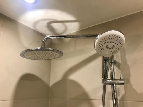 a shower head and its shadow on a wall at VULTOR Apartments in Wrocław