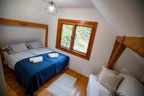 a bedroom with a bed and a window and a chair at Chata Pod Lasem in Poręba