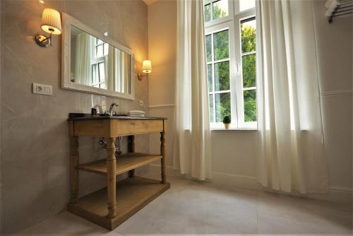 a bathroom with a table and a mirror and a window at Villa de Noailles in Spa
