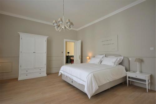 a white bedroom with a bed and a chandelier at Villa de Noailles in Spa