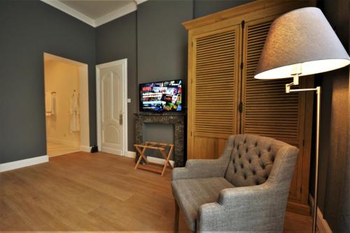 a living room with a chair and a television at Villa de Noailles in Spa