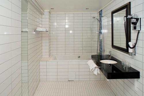 a white tiled bathroom with a sink and a shower at Quality Hotel Prinsen in Trondheim