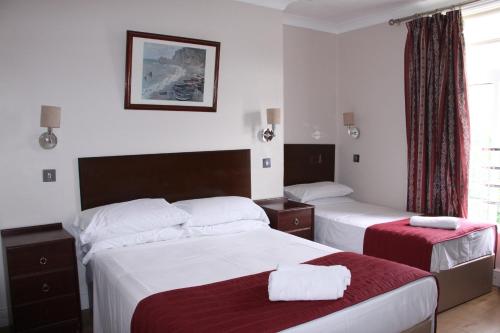 a hotel room with two beds and a window at Ambassador Hotel in Brighton & Hove