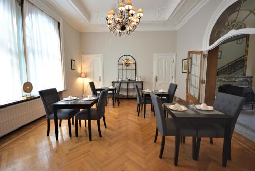 a dining room with black tables and chairs and a chandelier at Villa de Noailles in Spa