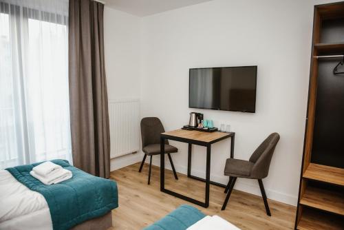 a hotel room with a desk and a tv and a bed at VILLA 17 Noclegi in Płock