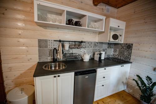a kitchen with white cabinets and a sink at Chata Pod Lasem in Poręba