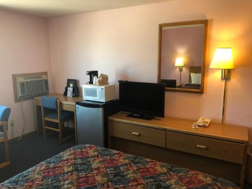a hotel room with a bed and a desk with a television at Executive Inn in McPherson