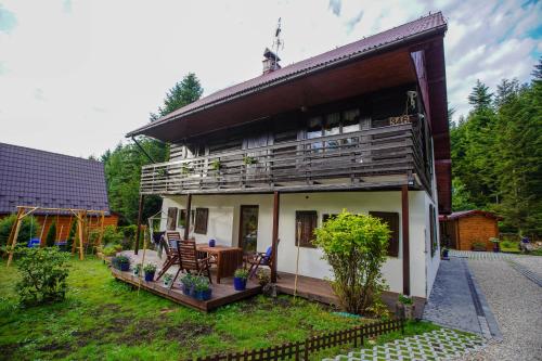 a house with a deck with a table and chairs at Chata Pod Lasem in Poręba