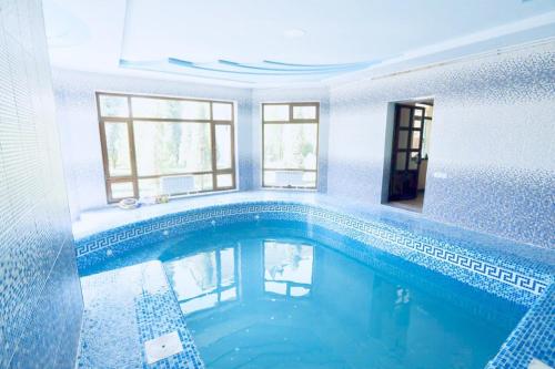 una grande piscina in una casa con piastrelle blu di Mavie Guest House a Tashkent