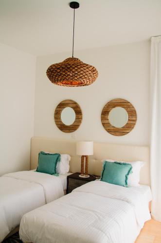 two beds in a room with round mirrors on the wall at Atlantis Gardens in Mazotos