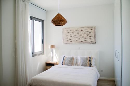 a white bedroom with a bed and a window at Atlantis Gardens in Mazotos