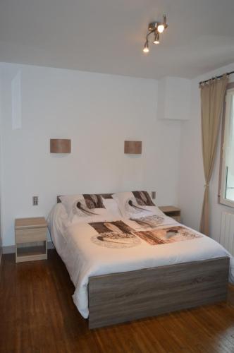 a bedroom with a bed with white sheets and a window at L'Acheneau in Marennes