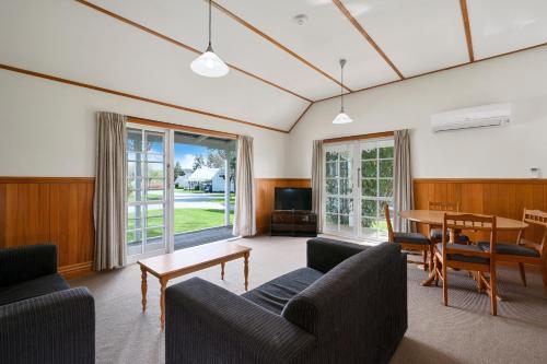a living room with couches and a table and a television at Huka Falls Resort in Taupo