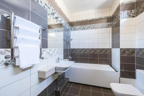 a bathroom with a tub sink and a toilet at Black Pearl Apartments in Jūrmala