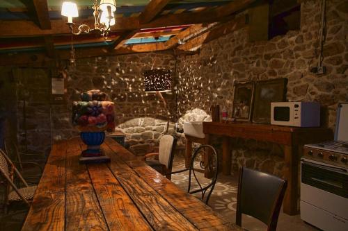 - un salon avec une table en bois et un mur en pierre dans l'établissement La Grande Serve, à La Chabanne