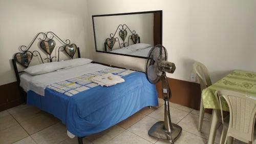 ein Schlafzimmer mit einem Bett und einem Ventilator neben einem Tisch in der Unterkunft Hostal Nuevo Amanecer in El Coca
