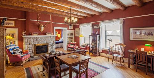 a living room with a table and a fireplace at Casa del Gavilan Historic Inn in Cimarron