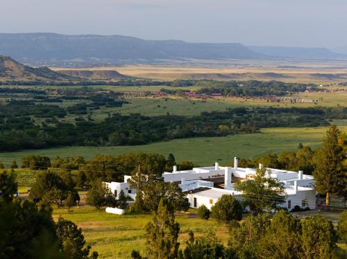 a large white house in a field with trees at Casa del Gavilan Historic Inn in Cimarron