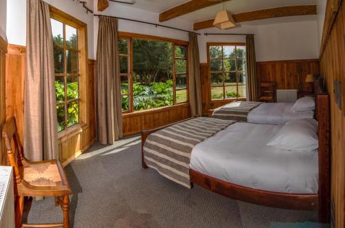 2 camas en una habitación con ventanas en Andes Lodge, Puelo Patagonia, en Puelo