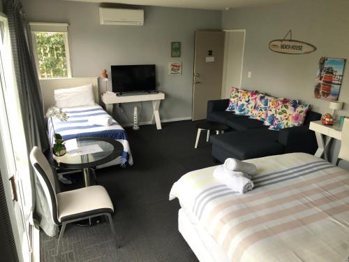 a room with two beds and a table and a television at Sandy Feet Accommodation in Christchurch