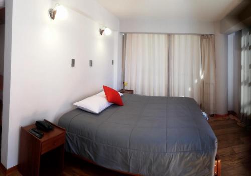 a bedroom with a bed with a red pillow on it at Real House Cusco in Cusco