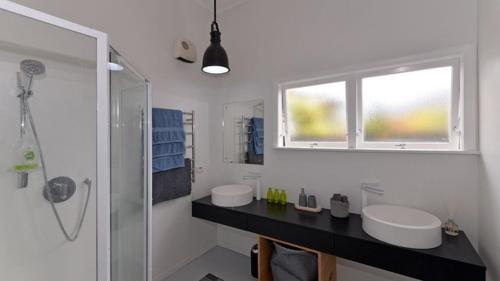 ein weißes Bad mit 2 Waschbecken und einem Fenster in der Unterkunft GROVE HOUSE in Nelson