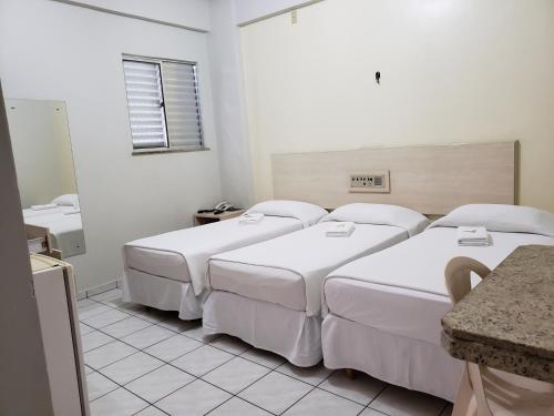 a hotel room with three beds and a mirror at Hotel Danúbio in Belém