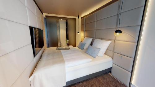- une petite chambre avec un lit blanc et un miroir dans l'établissement White Pearl Apartment 2.12, à Timmendorfer Strand