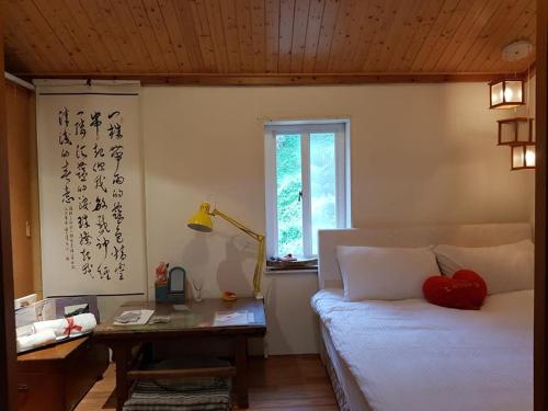 a bedroom with a bed and a desk and a window at Eternal Seaside House in Nangan