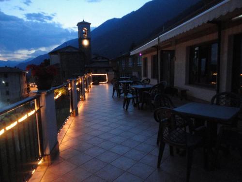 a balcony with tables and a clock tower at night at Albergo Ristorante Baraglia in Mello