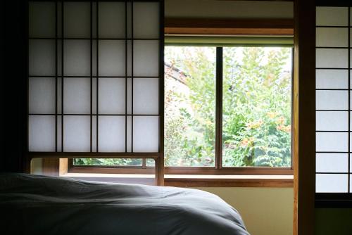 1 dormitorio con ventana y 1 cama en la parte delantera en Hyotan TABI-NE, en Kanazawa