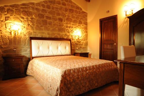 a bedroom with a bed and a stone wall at Grotta Biscia in Genazzano