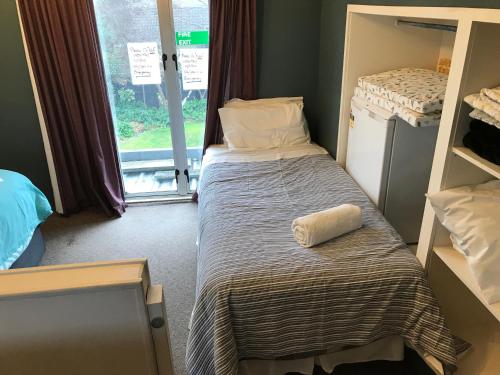 a small bedroom with a bed and a window at Sandy Feet Accommodation in Christchurch