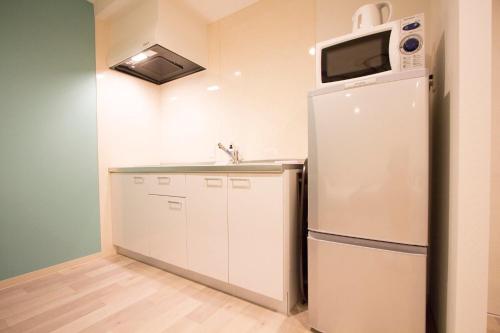 a kitchen with a white refrigerator and a microwave at Hokkaido Asahikawa 7 - inn in Asahikawa