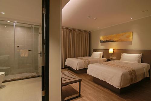 a hotel room with two beds and a shower at Home Inn Plus Lanzhou Zhangye Road Pedestrain Street in Lanzhou