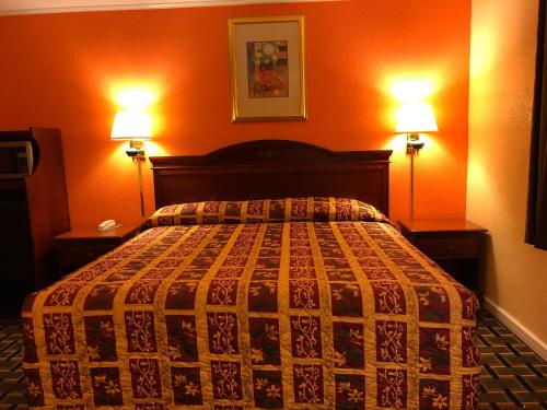 a bedroom with a bed with two lamps on both sides at Deluxe Inn in Natchez