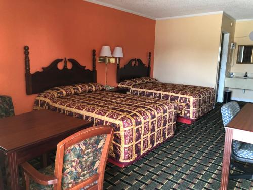 um quarto de hotel com duas camas e uma mesa e cadeiras em Deluxe Inn em Natchez