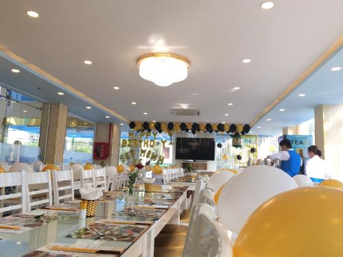a dining room with white chairs and tables with food at Khách sạn Sunrise Ninh Thuận in Thôn Dư Khánh