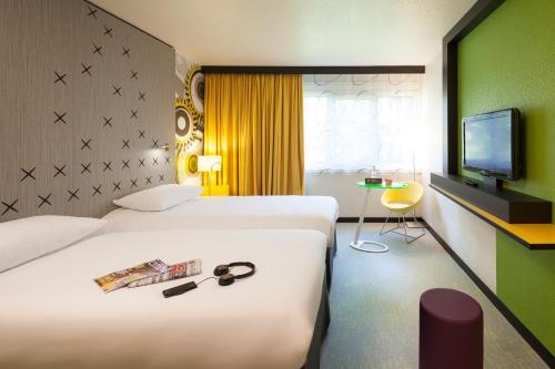 a hotel room with two beds and a television at ibis Styles Besan&ccedil;on in Besan&ccedil;on
