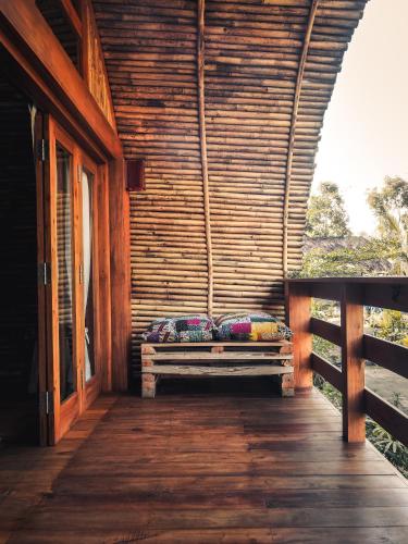 a wooden porch with a bench with pillows on it at Lagoona Beach Bungalows - Eco Bungalows Batukaras in Batukaras