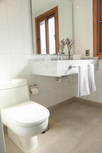 a white bathroom with a toilet and a sink at Leonera Hotel in La Leonera