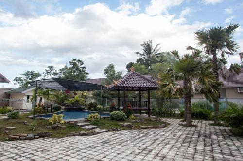 un patio trasero con piscina y cenador en RedDoorz Syariah Plus near Banyuwangi Airport, en Dadapan