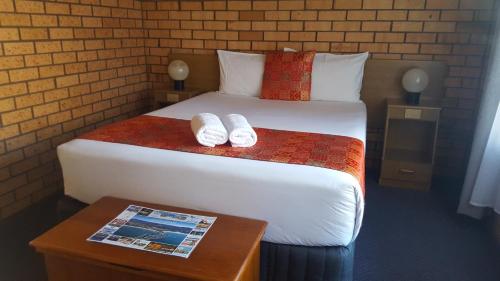 a bedroom with a bed with two slippers on it at Royal Palms Motor Inn in Coffs Harbour
