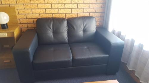 a blue leather couch in a room with a brick wall at Royal Palms Motor Inn in Coffs Harbour