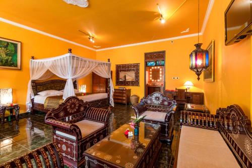a room with a bedroom with a bed and chairs at Tanah Merah Art Resort by AGATA in Ubud