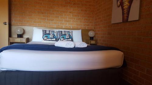 a bedroom with a large bed with towels on it at Royal Palms Motor Inn in Coffs Harbour