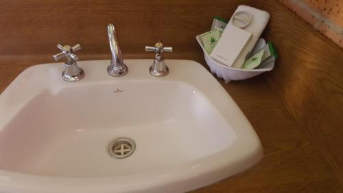 a white sink in a bathroom with a soap dispenser at Royal Palms Motor Inn in Coffs Harbour