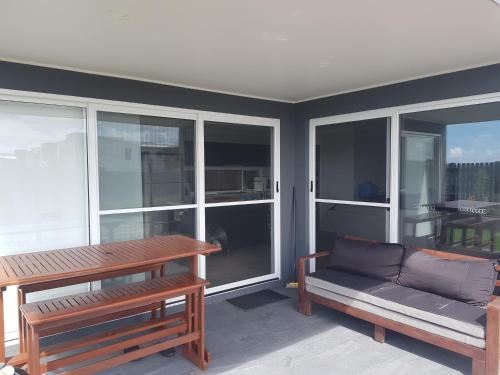 a living room with a couch and a table and windows at Hampton Homestay in Palmview